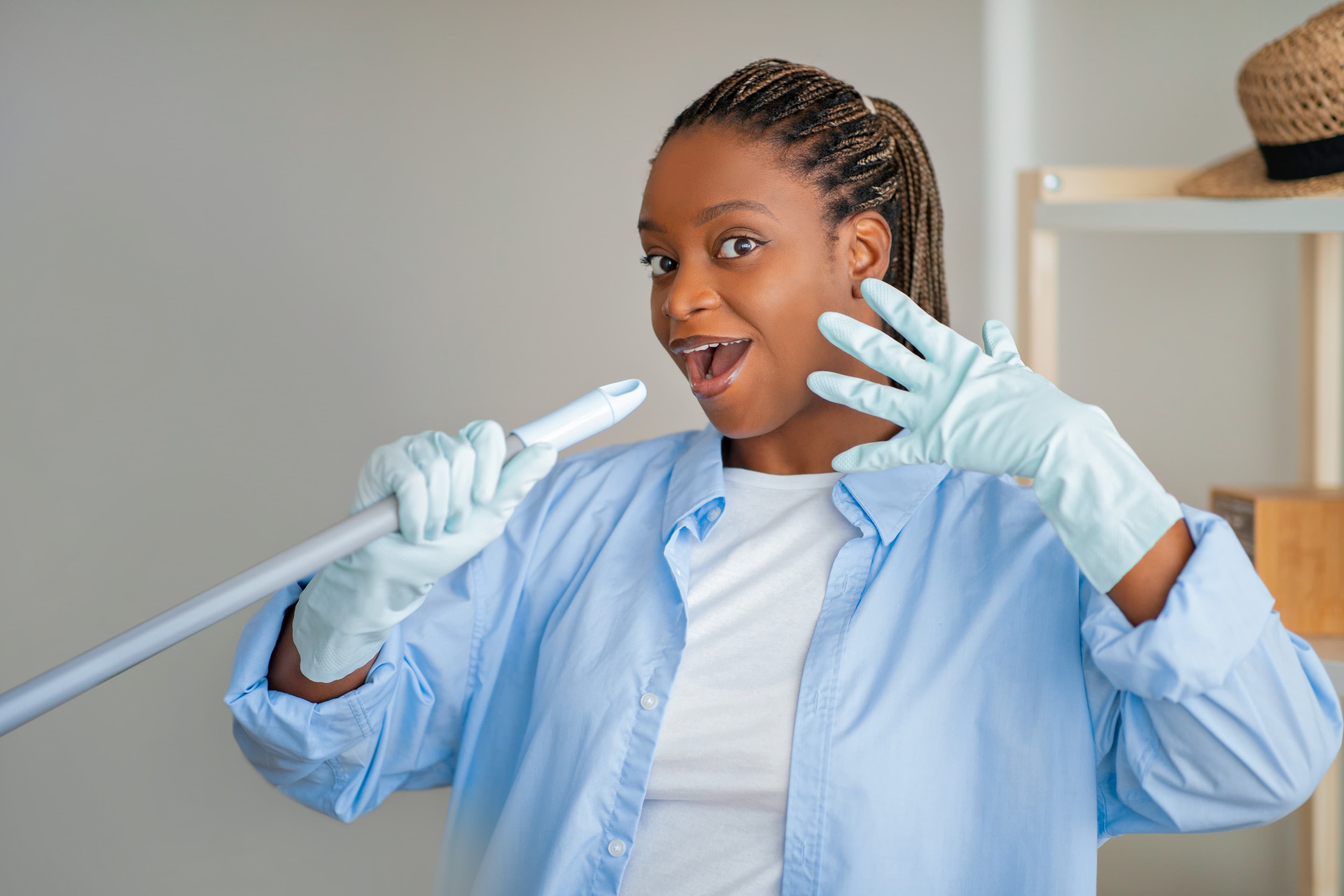 A cleaner in gloves singing into a mop handle
